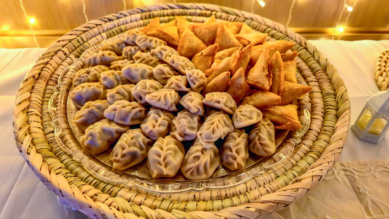A delicious assortment of dumplings and samosas elegantly displayed on a wicker tray.