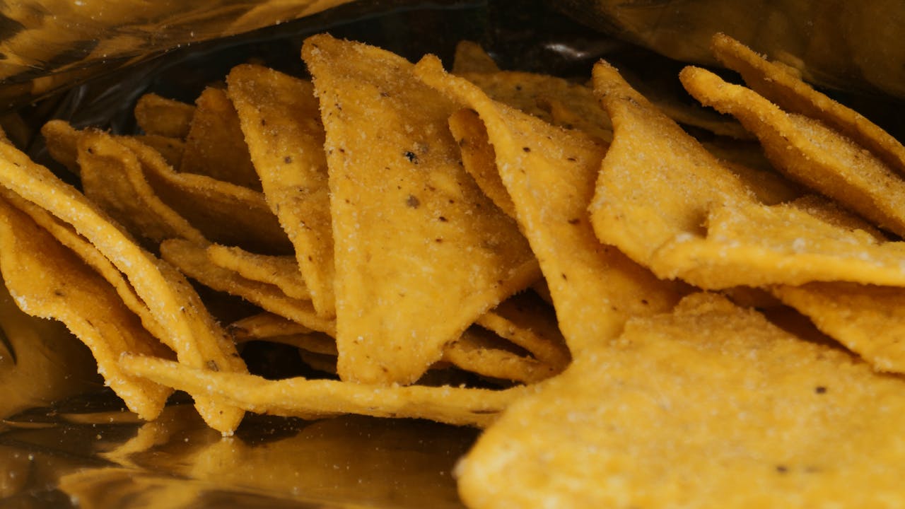 A detailed view of crispy nacho chips inside a metallic snack package.